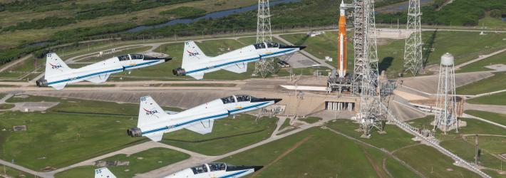 NASA T-38s fly in formation above the Space Launch System rocket on Launch Pad 39B.