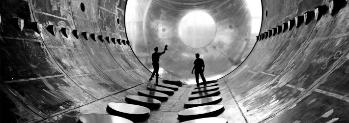 Two workers in a large vacuum tank.