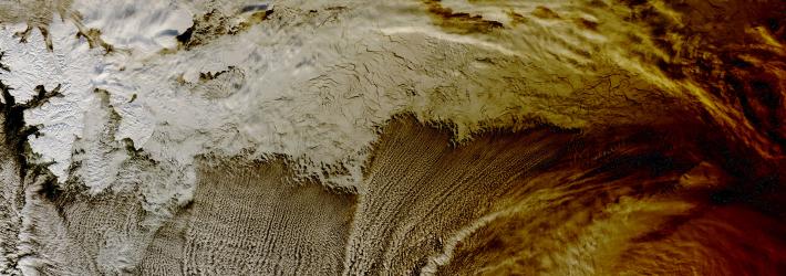 Clouds over the Arctic Ocean almost look like the sea's waves in this image from NASA's Terra satellite. The right side of the image has a brown-orange hue, almost like coffee with a little cream in it, due to the eclipse's shadow passing over them.