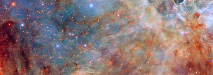 Shades of white, orange, and blue sweep across this view of the Large Magellanic Cloud. Blue and red stars peek through the clouds of gas and dust.