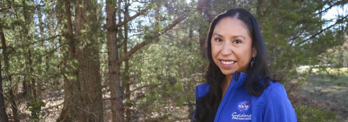 Miranda Meyer, a Native American woman, poses for a portrait amid trees.