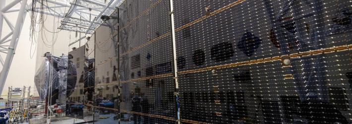 Large black rectangular solar arrays stretch out from the foreground to the back.